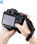 Person holding camera with Pro Mirrorless Camera Hand Grip Strap With Arca Type Plate, adjustable wrist guard in use.