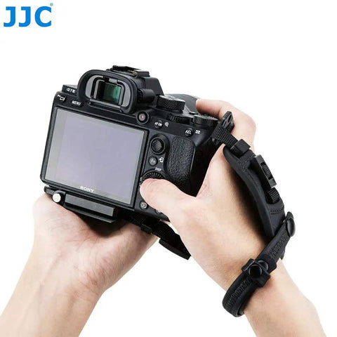 Person holding camera with Pro Mirrorless Camera Hand Grip Strap With Arca Type Plate, adjustable wrist guard in use.