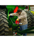 A person using the Heavy Duty Cordless Two Speed High Flow Grease Gun Kit Runs Slick with tractor maintenance.
