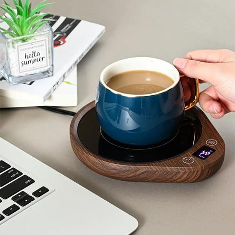 Keep Your Daily Drip Stayin Toasty With This Electric Coffee Mug Warmer Featuring Three Custom Temperature Levels Four Hour Auto Shut Off And Compact Desk Base For Zero Cold Sip Regrets. Blue ceramic mug on wooden electric warmer next to a laptop.