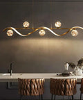 Modern Linear Pendant Light Set Featuring Six Glass Globe Shades Dimmable Gold Kitchen Island Fixture illuminating a sleek dining space.