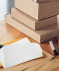 100 Pcs White Foam Pouches for Fragile Packing on wooden desk with boxes and shipping materials