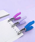Three-pack one hole puncher for paper crafts with purple soft grip handle, shows metal body, punches on lined paper, quarter inch hole size.