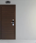 Lit LED Emergency Light With Manual Testing, 220 Lumens, Black, mounted above a dark wooden door in a commercial hallway