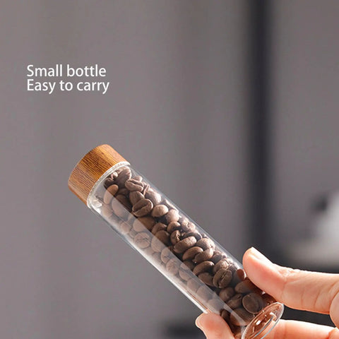 Keep Your Daily Coffee Run Fresh With This Top Tier Airtight Single Dose Bean Cellar Crafted From Genuine Walnut Wood And Clear Glass Tubes Designed To Be Hella Dope On Any Modern Counter While Blocking Out That Stale Funky Taste, small clear glass tube with walnut cap holding coffee beans.