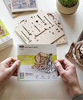 160 Piece Wooden Interlocking Puzzle Kit With Laser Cut Sustainably Sourced Plywood Real Wood Scent Easy Sanding Or Wax Finish Clear Manual Built For Brain Teasers And Creative Hands On Fun, boxed kit held over wooden puzzle parts
