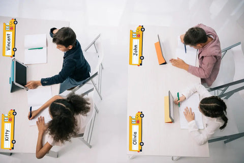 School Bus Themed Desk Name Tags Set With 36 Self Adhesive Name Plates For Classrooms on student desks in classroom setting.