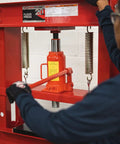 Person operating 20 Ton Hydraulic Shop Press For Gear Bearing And Bushing Removal Straightening And Bending Heavy Duty Industrial Grade Beast With 8.5 Inch Stroke Bottle Jack Reinforced Head Plate Built For Pros, focusing on red bottle jack and springs.