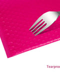 Close-up of a fork on pink bubble mailer, showing tearproof cushioning. Pink Bubble Mailers 8.5x11 Inch 30 Pack Waterproof Padded Envelopes.