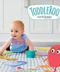 Baby crawling on a colorful play mat with Toddleroo by North States logo, showcasing playful safety for homes.