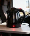 RigReady 24V 250W Portable Electric Kettle For Trucks And Rv on table, black, 1 liter capacity, auto shutoff feature.