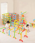 Two children playing with the No Fuss Learning 156 Piece Pipe Building Blocks Set, colorful interlocking tubes.