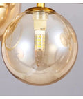 Close-up of glass ball pendant light in a modern chandelier for dining room, featuring LED bulb and gold accents.