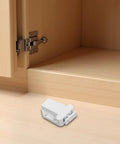 Push To Open Cabinet Hardware 8 Pack Self Closing Latch for kitchen cabinets, close-up of single white latch on wooden surface.