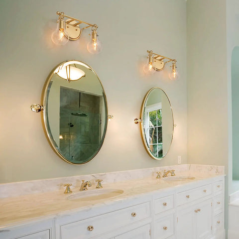 Two Light Gold Vanity Light With Clear Glass Shades For Bathroom above oval mirrors, modern decanter style fixture