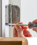 Person installing durable mini hinges for wooden boxes and jewelry boxes with nails in silver copper finish on a white door.