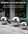 Three dope polished hollow stainless steel balls 201 grade, placed on pebbles for modern outdoor decor, 250mm diameter, 0.6mm wall thickness