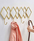 Dang Solid Wall Mount Coat Hook Featuring Heavy Duty Wrought Iron Craft With A Slick Rustic Copper And Gold Finish holding a pink scarf.