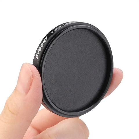 Hand holding 2-inch dark frame imaging filter for astrophotography, keeps night sky shots clean and pixel perfect by blocking sensor light.