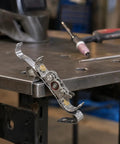 Ultimate TIG Wire Feeder Tool With Magnetic Base And Heat Shield For Alloy Filler Rods on a welding table.