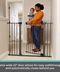 Parent holding baby next to Extra Tall And Wide Pressure Mounted Baby Gate For Doorways, 29.75 to 52 inches, graphite finish.