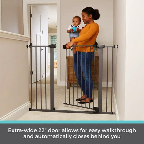 Parent holding baby next to Extra Tall And Wide Pressure Mounted Baby Gate For Doorways, 29.75 to 52 inches, graphite finish.