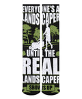 Knee-high socks with humorous landscaper text graphic, featuring a silhouette of a person mowing grass on a black and green background.