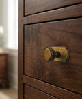 Close-up view of a vintage-style antique brass cabinet knob on dark wood cabinet, highlighting its design and material.
