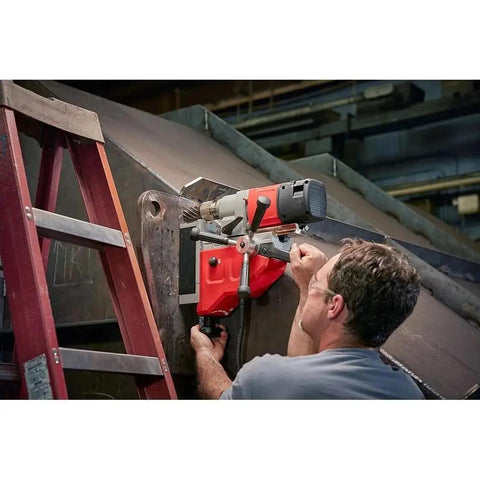 Man using Heavy Duty 1-5/8 Inch Magnetic Drill Base For Milwaukee Power Tools on 1/4 inch steel with a ladder.