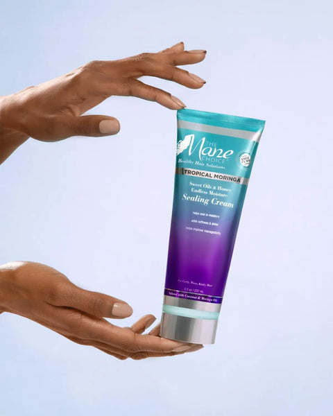 Hands holding Tropical Moringa Sweet Oil And Honey Endless Moisture Hair Cream For Curly Hair Defining Curls Frizz Control Deep Hydration Elasticity Boost Shine Lock In Lightweight Yet Rich Moisturizer 8 Ounce tube