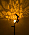 Solar Powered Garden Light with Crackle Glass Moon Ball on a Metal Stake casting glow, perfect for patio and lawn decor.