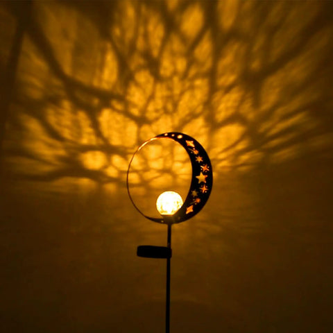 Solar Powered Garden Light with Crackle Glass Moon Ball on a Metal Stake casting glow, perfect for patio and lawn decor.