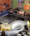Double-Sided Folding LED Work Light With 1000 Lumen Flood illuminating an engine bay in a workshop setting