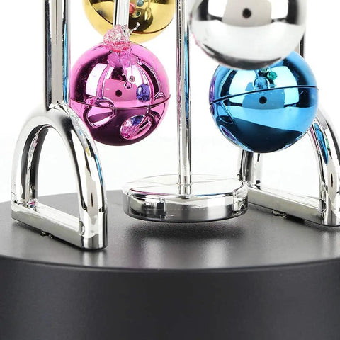 Close-up of Battery Powered Newton Pendulum Ball Desktop Toy with colorful mirrored balls on a plastic base, Newton's Cradle style.