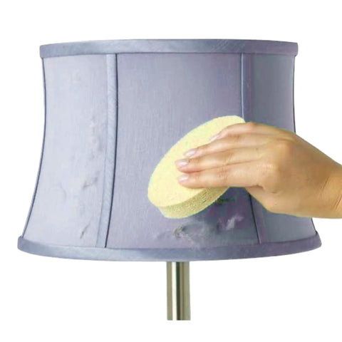 Hand using Easy To Use Sponge Lamp Shade And Fabric Cleaner For Delicate Fabrics And Lampshades, No Fuss Dust, Dirt, And Pet Hair Removal With Dry Magic, No Discoloration Risk, Hand Wash, Air Dry, And Reusable Clean In Between on a purple lampshade.