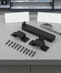 Heavy Duty Sliding Bar Gate Latch With Padlock Hole In Matte Black Metal For Outdoor Garden Sheds And Fences Built Tough With Straight Up Secure Locking Action That Is The Real Deal hardware kit with gate latch and screws on gray surface.