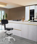 Grey rolling stool with back support in modern kitchen, hydraulic height adjustable swivel chair with four-inch thick cushion.