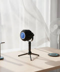 Top Shelf Acoustic Foam Microphone Windscreen And Pop Filter For Podcasting Creators And Live Streamers Chasing Crystal Clear Vocals With Tight Plosive Shielding In Sleek Black on a desk with a fan and a stand.
