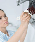 Woman using fin comb for air conditioner condenser and evaporator fins, coil cleaning brush and refrigerator coil cleaner