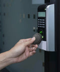 Hand using Dope 100 Pcs 13.56MHz UID Keyfobs for access control on electronic door reader
