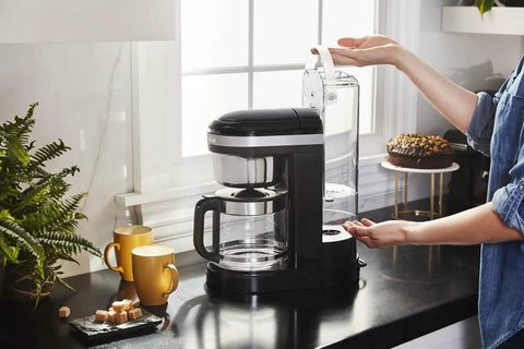 Side view of a 12 Cup Drip Coffee Maker With Spiral Showerhead And Programmable Keep Warm Plate For Rich Consistent Brews Every Time Onyx Black KCM1209 No Fuss Programmable Timer Auto Shutoff Large Water Reservoir For Busy Mornings on a kitchen counter