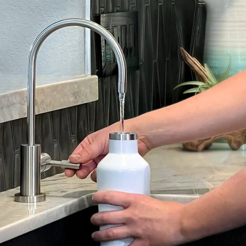 Person filling bottle at sink with Undersink Replacement Filter Cartridge For U9000 Systems, 1000 Gallon Capacity, NSF ANSI Certified