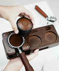 Person using Smooth Operator Wood Espresso Tamper Station with 51 and 58 mm coffee basket and wooden tamper in hand.