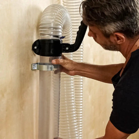 Man connecting 4 inch clear dust pipe to wall mount using quick connect coupler from Heavy Duty Dust Collection Floor Sweep And 4 Inch Clear Dust Pipe Accessory Kit.
