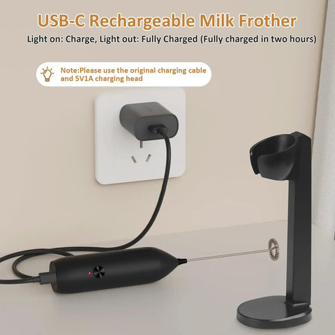 Rechargeable USB Type C Milk Frother Handheld With Stand shown charging with USB-C cable, black color, stand beside it.