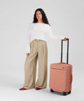 Person standing with Softside Bigger Carry On Luggage 23 Inch Expandable With Spinner Wheels Built Tough Nylon TSA Accepted Cloud Gray
