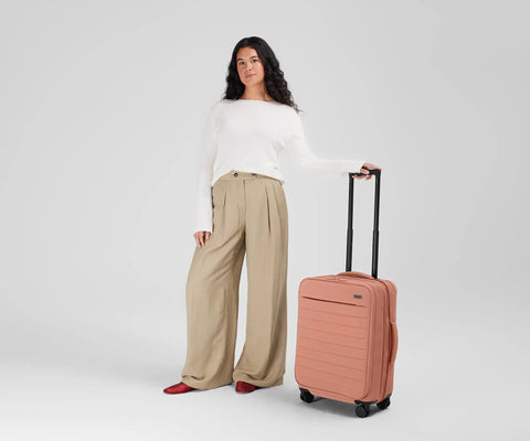Person standing with Softside Bigger Carry On Luggage 23 Inch Expandable With Spinner Wheels Built Tough Nylon TSA Accepted Cloud Gray