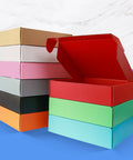 Stack of colorful cardboard boxes with one red box open, showing various colors for Grey Cardboard Shipping Boxes Pack Of 20 Lightweight Corrugated Mailer Boxes For Ecommerce Packaging L8xW5.5xH1.5 Inches Durable Fulfillment Boxes Ideal For Small Biz.