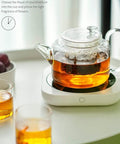 Keep Those Daily Brews Popping With This Touch Control Coffee Mug Warmer And Electric Cup Heater Featuring Dual Heat Settings For Flat Bottom Drinkware Fast Forty Nine Watt Warmth Plus Ten Hour Auto Shutoff To Ride The Comfort Wave Anytime - glass tea pot on warmer with brewed tea.