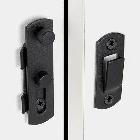 Close-up of a matte black barn door latch installed on a white door, from the Four Pack Matte Black Stainless Steel Barn Door Latches 2.75 Inch By 2.02 Inch Built To Last Heavy Duty Flip Bi Fold Sliding Door Lock For Barn Gates Closet Wine Cabinet Cabinetry And Rustic Home Decor.